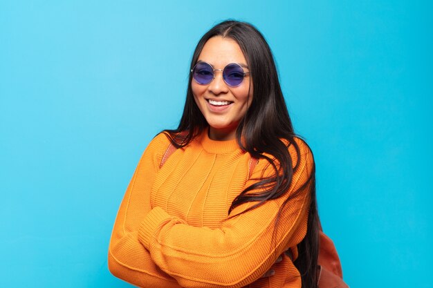 Young latin woman laughing happily with arms crossed, with a relaxed, positive and satisfied pose