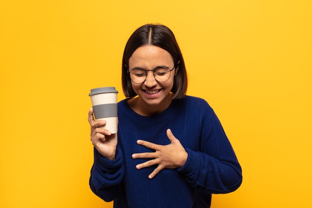 Young latin woman laughing out loud at some hilarious joke, feeling happy and cheerful, having fun