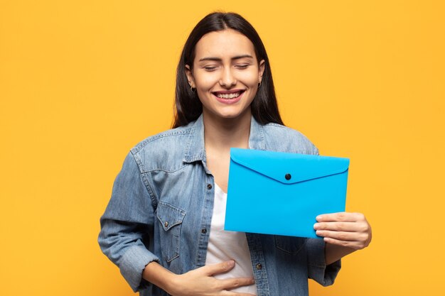 Young latin woman laughing out loud at some hilarious joke, feeling happy and cheerful, having fun