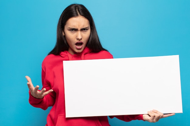 Young latin woman looking angry, annoyed and frustrated screaming what's wrong with you