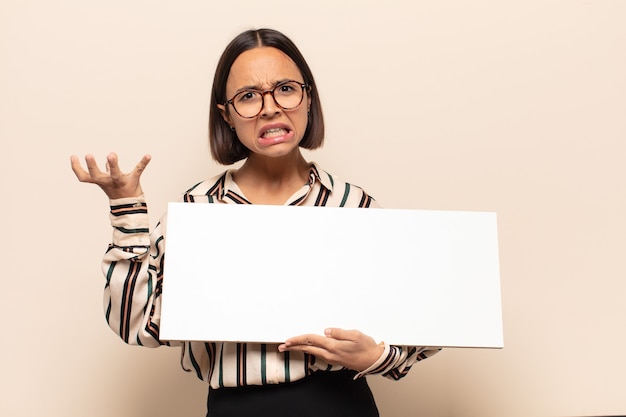 Young latin woman looking angry, annoyed and frustrated screaming wtf or whatÃÂ¢ÃÂÃÂs wrong with you