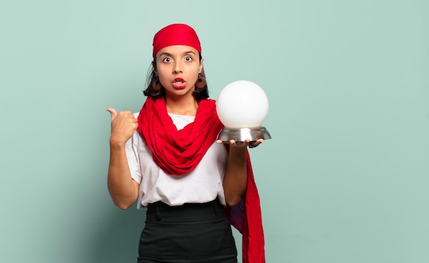 Young latin woman looking astonished in disbelief, pointing at object on the side and saying wow, unbelievable