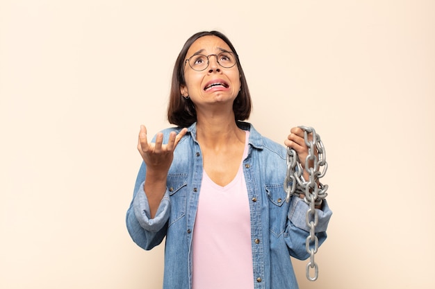 Young latin woman looking desperate and frustrated, stressed, unhappy and annoyed, shouting and screaming