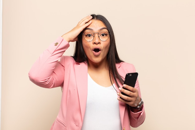 Young latin woman looking happy, astonished and surprised, smiling and realizing amazing and incredible good news