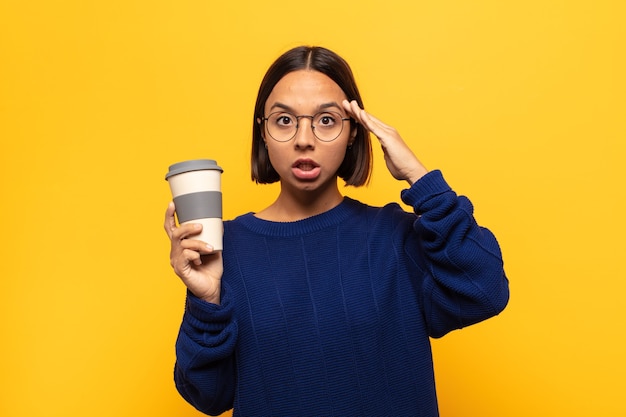 ラテン系の若い女性は、幸せそうに見え、驚き、驚き、笑顔で、驚くべき信じられないほどの良いニュースを実現しています。