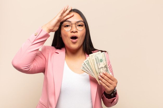 Young latin woman looking happy, astonished and surprised, smiling and realizing amazing and incredible good news