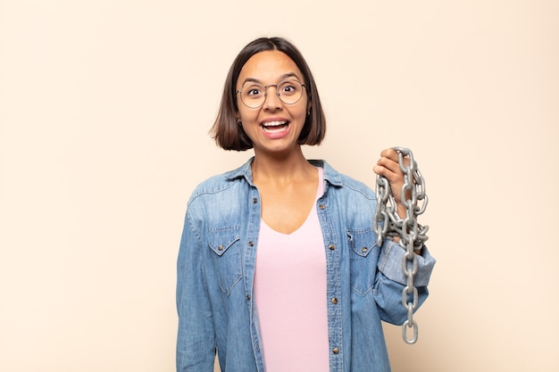 Young latin woman looking happy and pleasantly surprised, excited with a fascinated and shocked expression