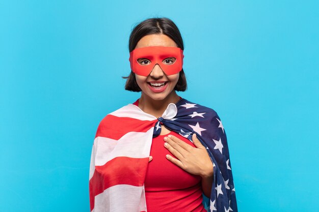 Young latin woman looking happy, surprised, proud and excited, pointing to self