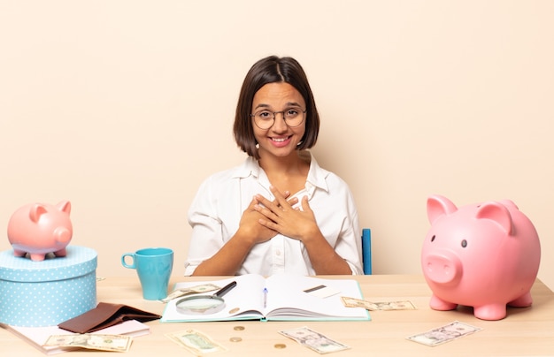 Young latin woman looking happy, surprised, proud and excited, pointing to self