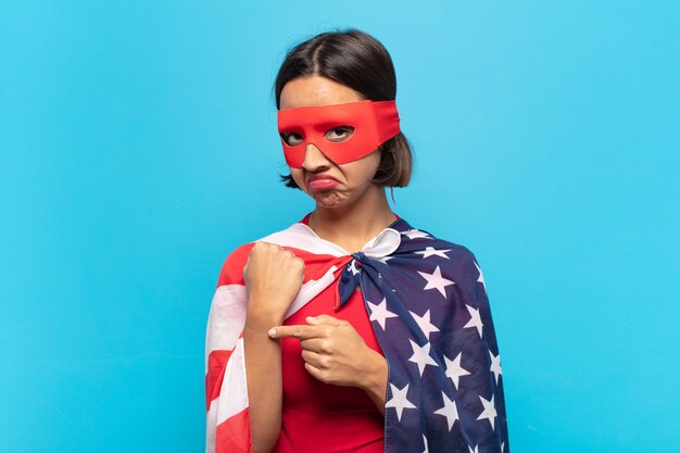 Young latin woman looking impatient and angry, pointing at watch, asking for punctuality, wants to be on time