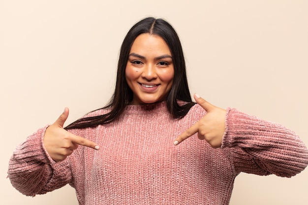 Young latin woman looking proud, arrogant, happy, surprised and satisfied, pointing to self