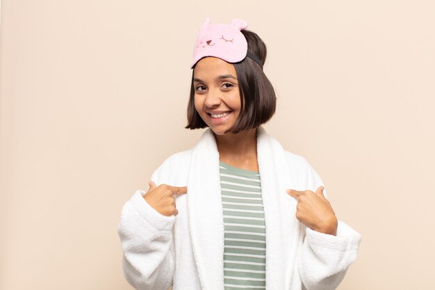 Young latin woman looking proud, confident and happy, smiling and pointing to self or making number one sign