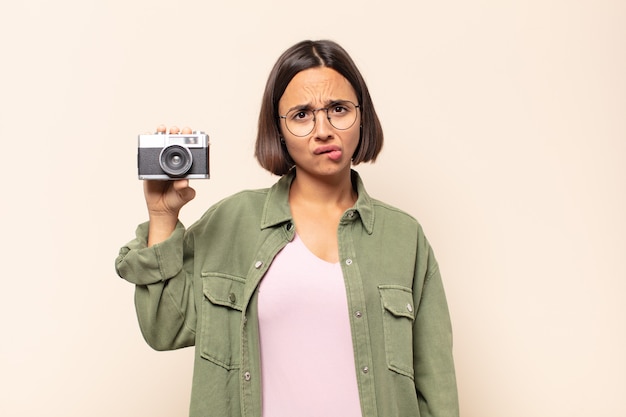 Photo young latin woman looking puzzled and confused, biting lip with a nervous gesture, not knowing the answer to the problem