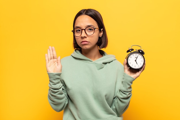 写真 真面目で、厳しく、不機嫌で、怒っているように見える若いラテン女性は、開いた手のひらを停止ジェスチャーを示しています