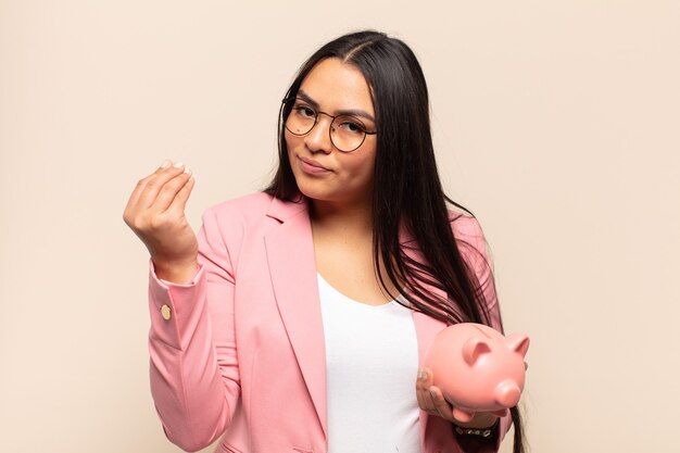 Young latin woman making capice or money gesture, telling you to pay your debts!