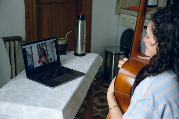 Photo young latin woman in online guitar lessons with her laptop at home