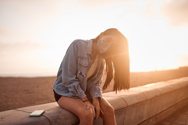 Foto giovane donna latina pone camminando sulla sabbia durante un bel tramonto felice giovane donna con maschera