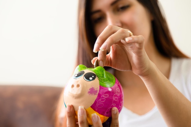 Young latin woman saving her money on her colorful pig