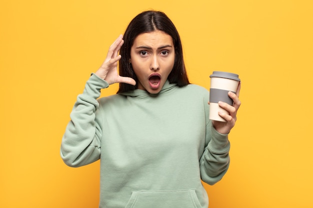 young latin woman screaming with hands up in the air, feeling furious, frustrated, stressed and upset