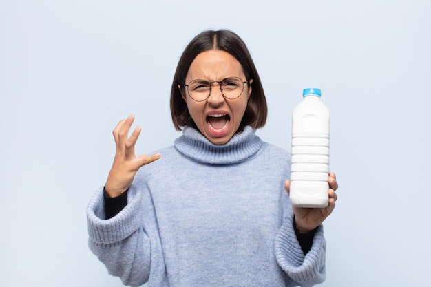 young latin woman screaming with hands up in the air, feeling furious, frustrated, stressed and upset