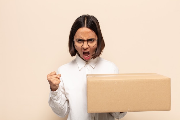 Young latin woman shouting aggressively with an angry expression or with fists clenched celebrating success