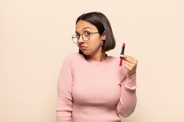 Young latin woman shrugging, feeling confused and uncertain, doubting with arms crossed and puzzled look