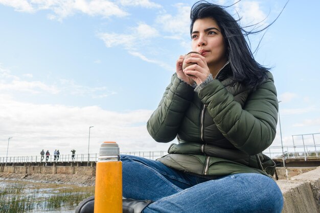 young latin woman sitting outdoors enjoying morning drinking mate copy space