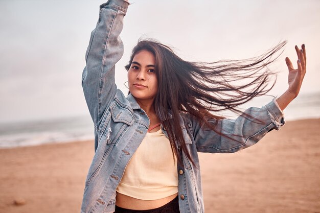 Young Latin woman smiles during a beautiful sunset Happy young woman with mask on the beach taking