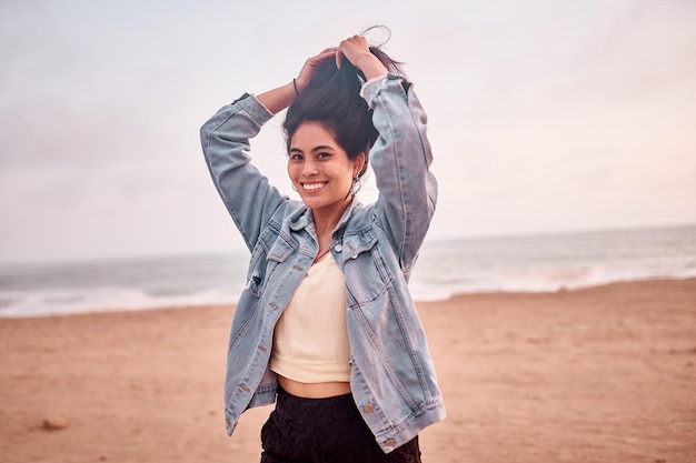 Young Latin woman smiles during a beautiful sunset Happy young woman with mask on the beach taking