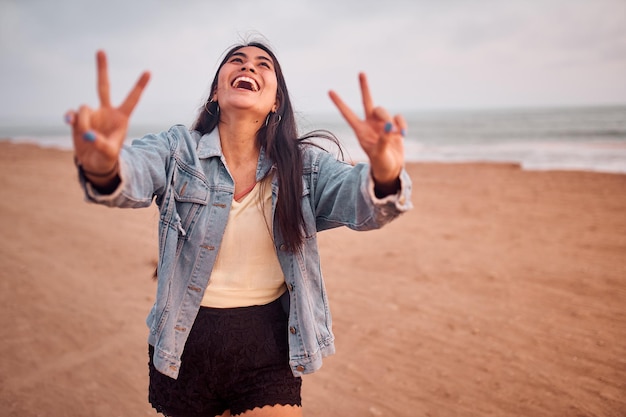 Young Latin woman smiles during a beautiful sunset Happy young woman with mask on the beach taking