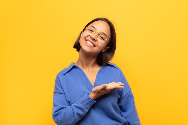 Young latin woman smiling cheerfully, feeling happy and showing a concept