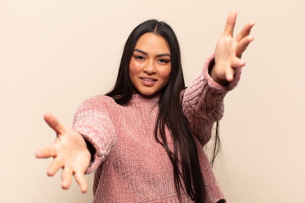 Young latin woman smiling cheerfully giving a warm, friendly, loving welcome hug, feeling happy and adorable