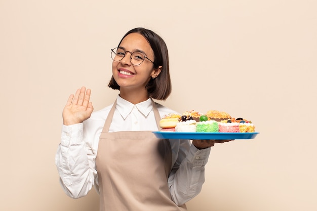 ラテン系の若い女性が楽しく元気に笑ったり、手を振ったり、歓迎して挨拶したり、さようならを言ったりします。