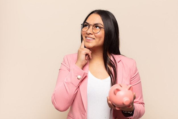 Young latin woman smiling happily and daydreaming or doubting, looking to the side