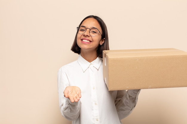 Young latin woman smiling happily with friendly, confident, positive look, offering and showing an object or concept