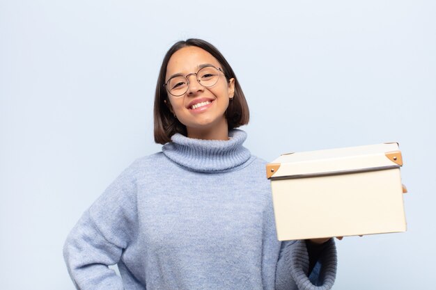 Young latin woman smiling happily with a hand on hip and confident, positive, proud and friendly attitude