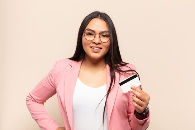 Young latin woman smiling happily with a hand on hip and confident, positive, proud and friendly attitude