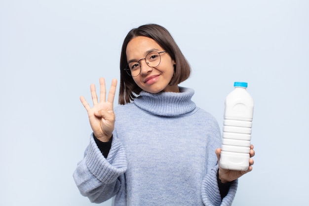 Young latin woman smiling and looking friendly, showing number four or fourth with hand forward, counting down