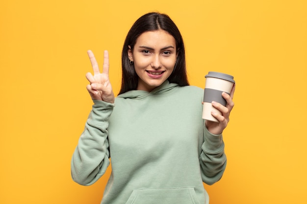 Young latin woman smiling and looking friendly, showing number two or second with hand forward, counting down