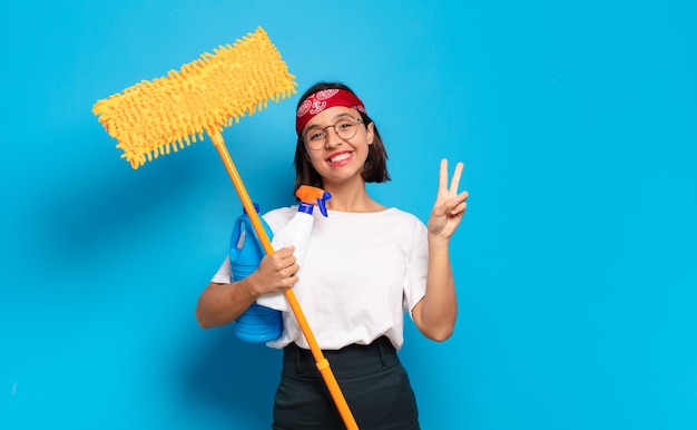 Young latin woman smiling and looking happy, carefree and positive, gesturing victory or peace with one hand