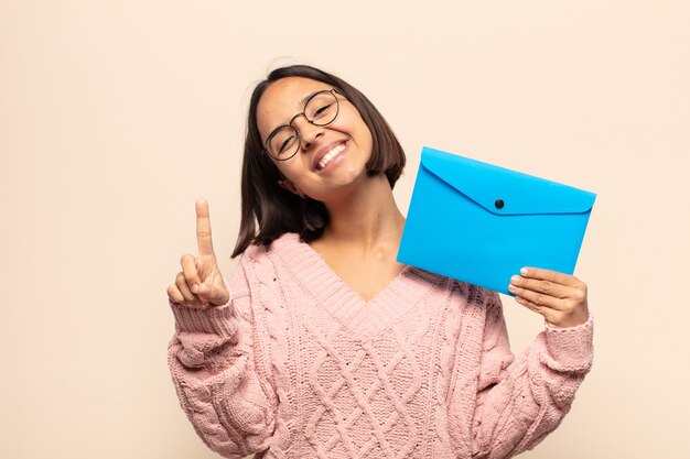 Young latin woman smiling proudly and confidently making number one pose triumphantly