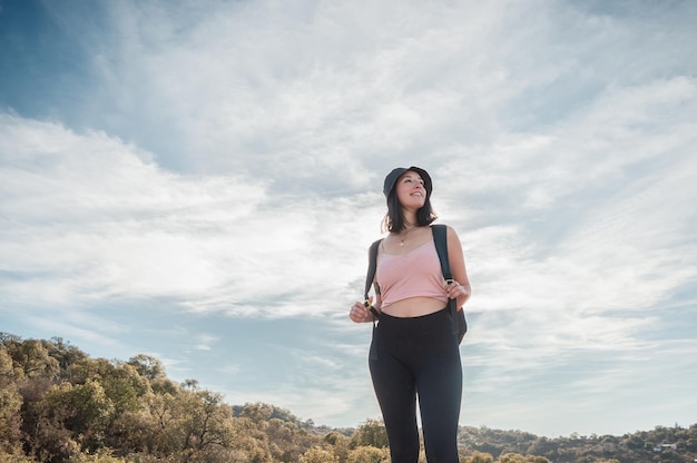 young latin woman standing on the road resting from her trek up the mountain