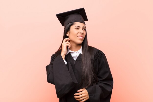 Giovane studentessa latina sentirsi stressata, frustrata e stanca, sfregando il collo doloroso, con uno sguardo preoccupato e turbato