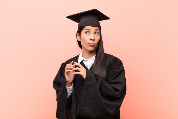 Young latin woman student scheming and conspiring, thinking devious tricks and cheats, cunning and betraying