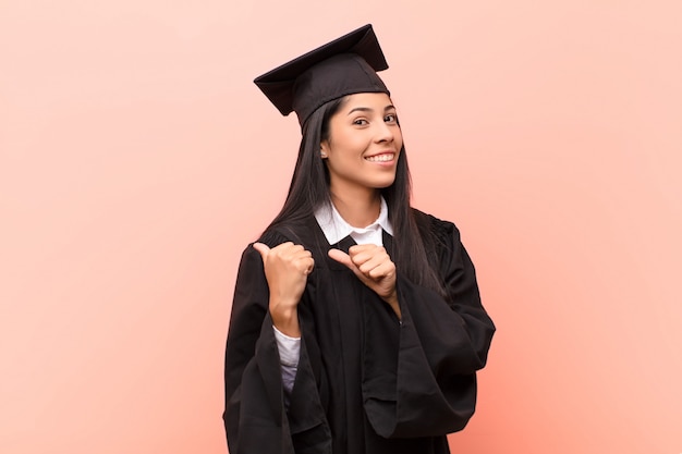 Young latin woman student smiling cheerfully and casually pointing to copy space on the side, feeling happy and satisfied