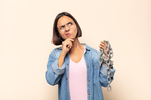 Young latin woman thinking, feeling doubtful and confused, with different options, wondering which decision to make