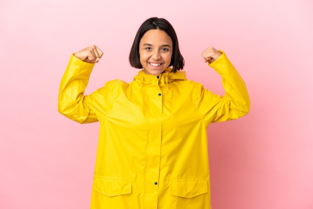 写真 強いジェスチャーをしている孤立した背景の上に防雨コートを着ている若いラテン女性