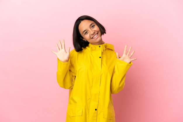 Young latin woman wearing a rainproof coat over isolated background counting ten with fingers