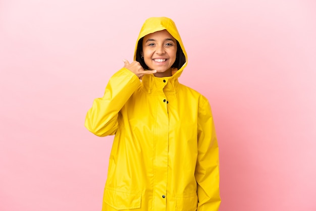 Foto giovane donna latina che indossa un cappotto antipioggia su sfondo isolato facendo gesto di telefono. richiamami segno