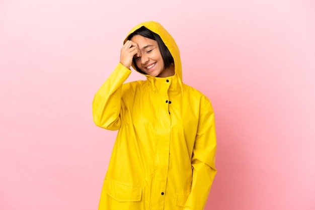 Photo young latin woman wearing a rainproof coat over isolated background smiling a lot